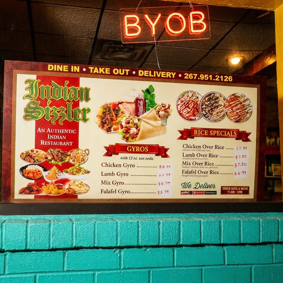 Restaurant window displays Indian Bistro menu with gyros, rice specials, food photos, and a glowing BYOB sign.